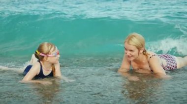 Anne ve kızı denizdeki sörf dalgalarında eğleniyorlar. Çocuklarla mutlu anlar.
