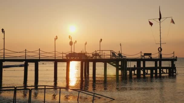 Рассвет над морем. Силуэт пирса, выходящего в воду - живописный пейзаж летнего отдыха — стоковое видео