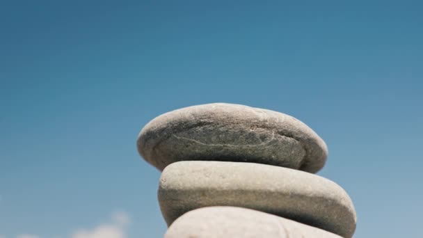 Man builds a pyramid of pebbles against the blue sky — Stock Video