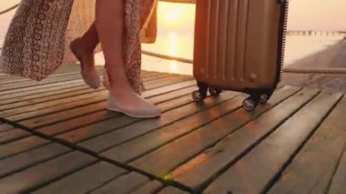 Parşömende bavulu olan bir turist deniz kıyısındaki tatil köyüne geldi ve iskele boyunca yürüdü.
