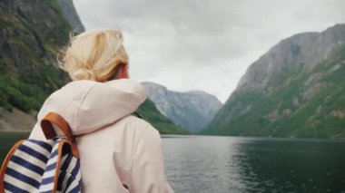 Bir yolcu gemisinin pruvasındaki turist Norveç 'teki fjord' a hayran.