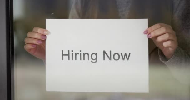 Employee hangs on the door ad Hiring Now — Stock Video