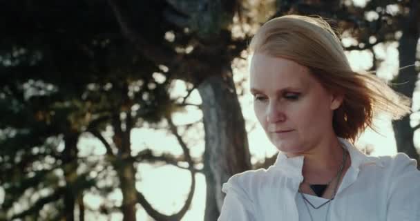 Portrait of a middle-aged woman standing in the woods in her hair blowing wind — Stock Video