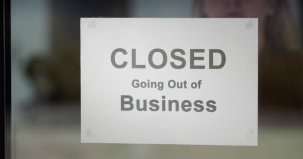 Работник удаляет и разрывает объявление ЗАКРЫТО, выходящее из бизнеса — стоковое видео