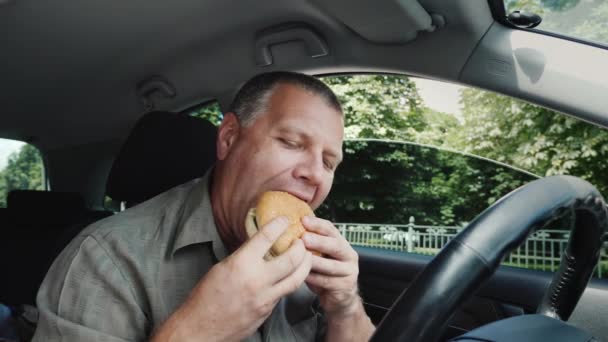 Πεινασμένος αρσενικός οδηγός τρώει άπληστα burger στο τιμόνι — Αρχείο Βίντεο