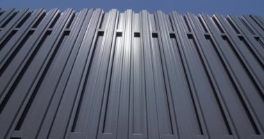Kaydırıcı atış: Gri metal şeritlerden yapılmış bir çit. Mavi gökyüzüne karşı