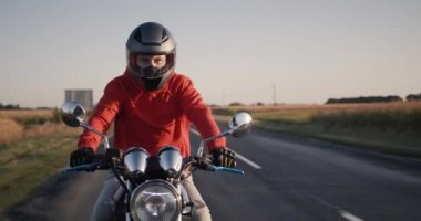 Bir sonbahar günü mısır tarlaları boyunca motosiklet süren genç bir motorcunun portresi