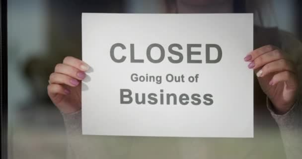 Worker hangs a banner CLOSED going out of Business on the door — Stock Video