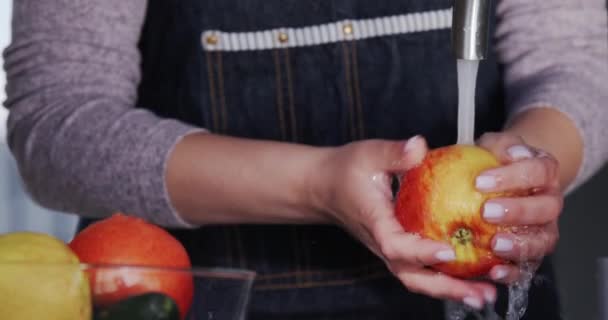 Egy nő egy szaftos vörös almát mos a csap alá.. — Stock videók