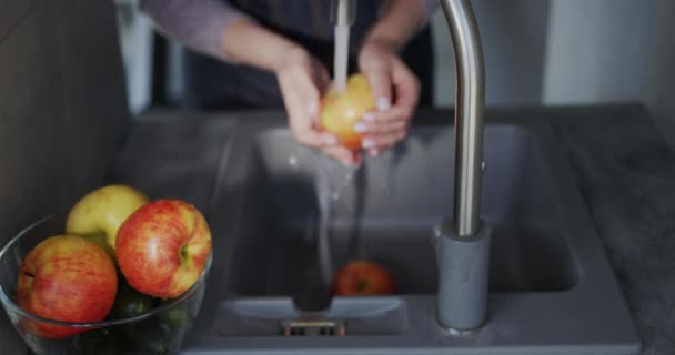Een vrouw wast een sappige rode appel onder een kraan. Bovenaanzicht — Stockvideo