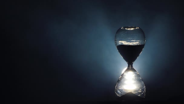 Hourglass σιλουέτα σε σκούρο φόντο όπου στροβιλίζεται καπνός — Αρχείο Βίντεο