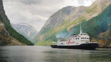 Flam, Norveç, Temmuz 2018: Turistli bir yolcu gemisi Norveç 'teki pitoresk fiyortun arka planına doğru kıyıya yaklaşıyor