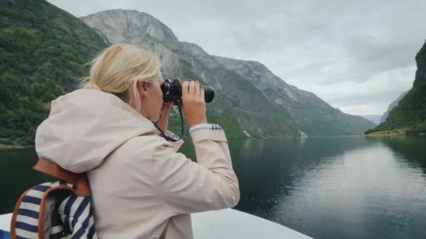 Kobieta sukcesu podróżuje po Norwegii, spogląda przez lornetkę na piękny krajobraz — Wideo stockowe
