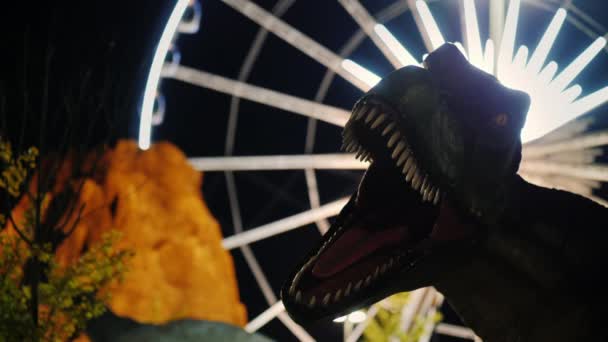 Niagara Falls, Ontario, Canada, september 2017: Een dinosaurus met een open mond. Op een achtergrond van een vulkaan en een reuzenrad in een pretpark — Stockvideo
