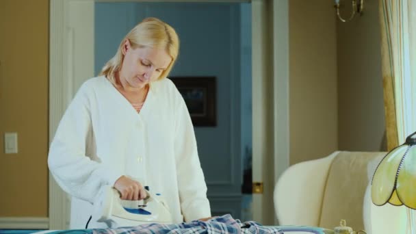 年轻的家庭主妇在家里烫衬衫 — 图库视频影像