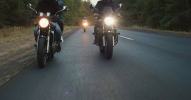 Bir grup motorcu otoyol boyunca gidiyor, çerçevede tekerlekleri ve farları görebilirsiniz.