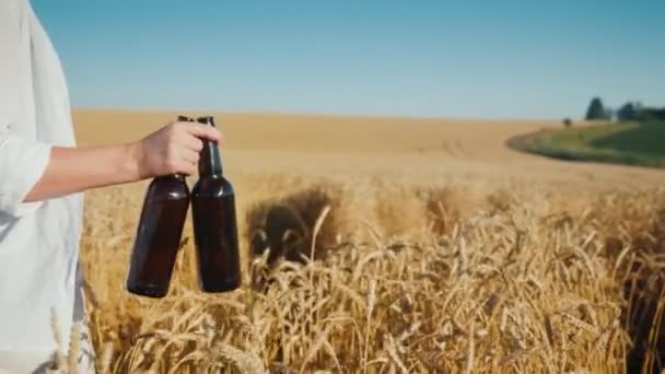 熟した小麦の上に2本のビールを運ぶ女性 — ストック動画