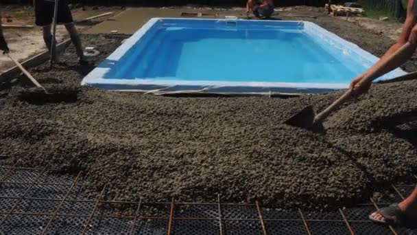 Ein Bautrupp nivelliert den Beton rund um das Becken. Bau eines Hotels mit Schwimmbad — Stockvideo