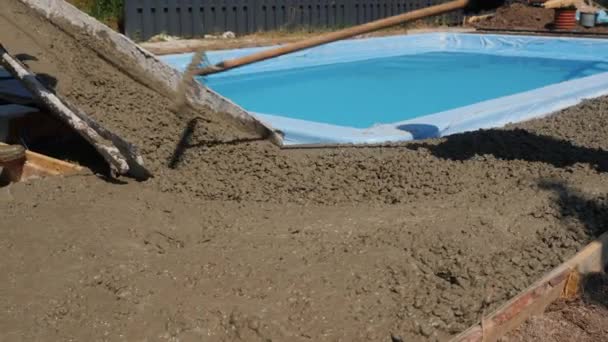Ein Bautrupp stellt Betonpflaster rund um den Pool her — Stockvideo