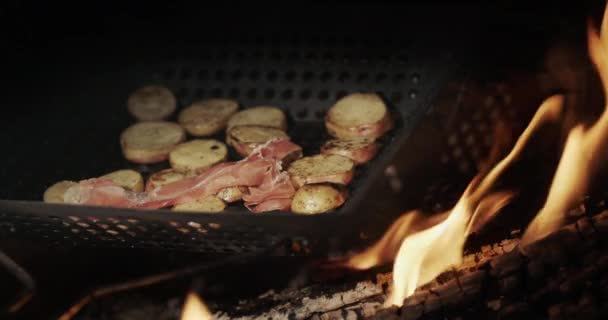 As batatas com partes de bacon fritam-se em uma panela de ato de fritar sobre uma fogueira aberta — Vídeo de Stock