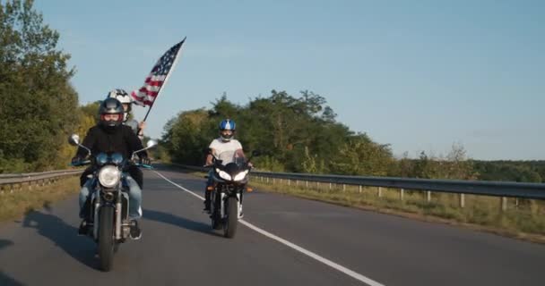 Mladí motorkáři řídit na dálnici s nimi americkou vlajku — Stock video