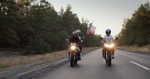 Junge Leute auf Hochgeschwindigkeitsmotorrädern fahren auf der Autobahn, ein Mädchen hält die US-Flagge hoch — Stockvideo