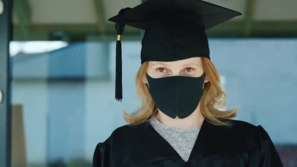 Porträt eines maskierten Absolventen vor der Tür der Universität — Stockvideo