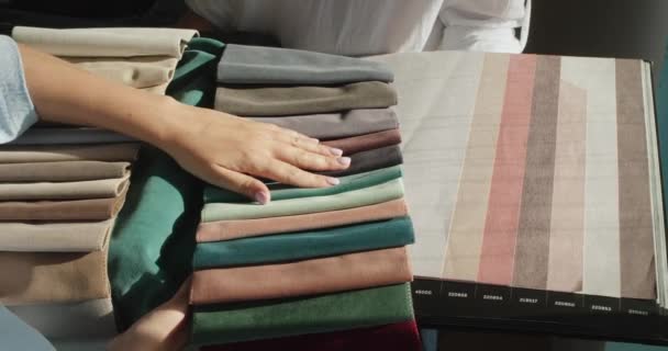 Žena kupující vyzvednout textilie v obchodě, porovnává odstín s katalogem tapet. Prodávající vlastní album se vzorky — Stock video