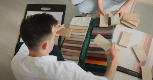El equipo de diseño selecciona materiales de acabado para su proyecto, compara muestras de tela, madera y papel pintado — Vídeo de stock