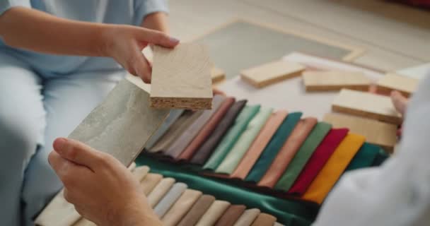 Tasarım ekibi projeleri için tamamlayıcı malzemeler seçiyor, kumaş, ahşap ve duvar kağıdı örneklerini karşılaştırıyor — Stok video