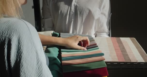 Uma mulher escolhe têxteis para reparação na casa, compara com imagens de papel de parede, seleciona cor e sombra — Vídeo de Stock