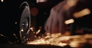 Metali tutan elektrikli bir aletle ustanın elleri. Kıvılcımlar etrafa saçıldı.