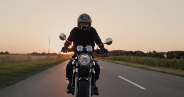 Молодой байкер едет по шоссе в лучах заходящего солнца — стоковое видео