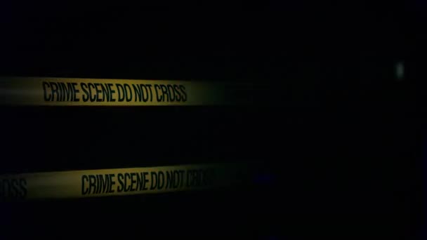 La escena del crimen está cubierta con cinta de advertencia, coches de policía están parpadeando en el fondo — Vídeos de Stock