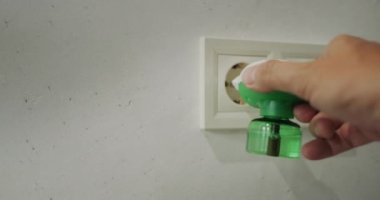 Adamın biri elektrik prizine bir buharlaştırıcı takıyor. Sivrisinekleri yok etmek için bir cihaz.