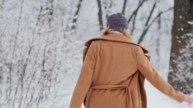Arkaya bakan mutlu kadın kış parkında yürümekten zevk alıyor.