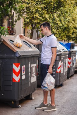 Roma 'da bir sokakta ev atığını sıralayan, gübre kutusuna yiyecek dolu bir çanta koyan, sorumlu atık yönetimi ve kentsel sürdürülebilirliği teşvik eden bir adam. Yüksek kalite fotoğraf