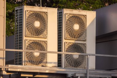 Sıcak gün batımı ışığı altında çatı havalandırma ve havalandırma sistemleri endüstriyel soğutma ve havalandırma ekipmanları açık havada. Yüksek kalite fotoğraf