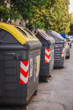 Roma, İtalya 'da bir iskan caddesinde atık ayıklamak, kentsel çevre sorumluluğu ve sürdürülebilirliği desteklemek için sarı ve kahverengi kapaklı geri dönüşüm konteynırları. Yüksek kalite fotoğraf