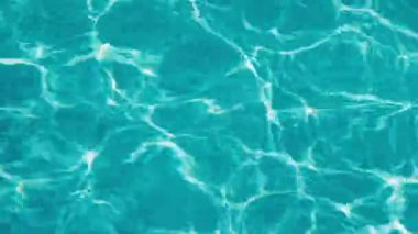 Güneş ışığı yansımalı temiz turkuaz su yüzeyi soyut dalgalı desenler yaratıyor. Yüksek kalite 4k görüntü
