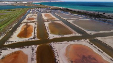 Santa Pola, Alicante, İspanya yakınlarındaki tuz buharlaştırma göletlerinin havadan görünüşü. Akdeniz kıyı şeridinde kırmızı ve kahverengi suyu olan geometrik havuzlar. Yüksek kalite 4k görüntü