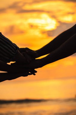 Denizin üzerinde parlayan gün doğumuna karşı bir birlik ve destek jesti olarak el ele tutuşun. Yüksek kalite fotoğraf