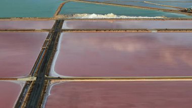 İspanya 'nın Santa Pola kenti yakınlarındaki pembe ve turkuaz tuz buharlaştırma göletlerinin hava yakın çekimleri, bölünen yollar boyunca toplanan tuz yığınları. Yüksek kalite 4k görüntü