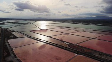 İspanya 'nın Santa Pola kenti yakınlarındaki renkli tuz buharlaşma göletlerinin havadan görünüşü, pembe ve yeşil su yüzeyleri bulutlu akşam gökyüzünü yansıtıyor. Yüksek kalite 4k görüntü