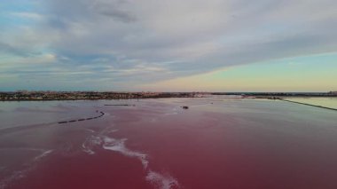 Pembe tuz gölü Laguna Salada de Torrevieja 'nın günbatımında havadan görünüşü, tuz çıkarma mavnaları ve kıyı kenti uzaktan görülebilir. Yüksek kalite 4k görüntü