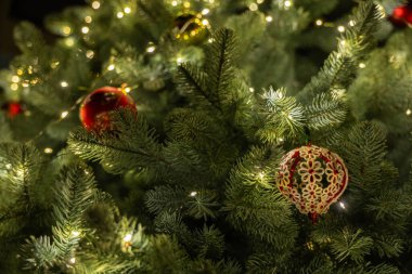 Parlayan ışıkları ve el yapımı süslemeleri olan Noel ağacı dallarına yakın çekim yaparak şenlikli bir kış atmosferi yaratıyor. Yüksek kalite fotoğraf