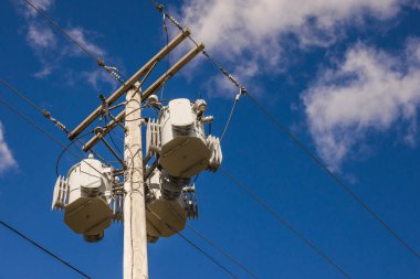 ABD 'de açık mavi gökyüzüne karşı çoklu elektrik transformatörleri ve elektrik hatları olan tahta elektrik direği. Yüksek kalite fotoğraf