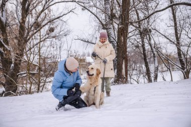 Yaşlı bir kadın ve yetişkin kızı kış günlerini Golden Retriever 'larıyla dışarıda geçiriyorlar. Kız, köpeğin yanında diz çöker, onu sevgiyle okşar, anne ise tasmayı bir köpeğin ortasında tutar.