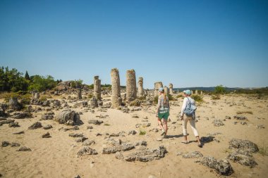 Bulgaristan 'ın Varna kenti yakınlarındaki Taş Çölü olarak da bilinen Pobiti Kamani' nin antik kireçtaşı sütunlarını parlak mavi bir yaz gökyüzü altında keşfeden iki kadın. Yüksek kalite fotoğraf