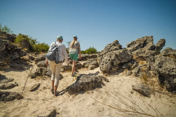 Bulgaristan 'da Pobiti Kamani' nin kumlu arazisi ve kayalık oluşumlarında parlak yaz güneşi altında yokuş yukarı yürüyen iki kadın. Yüksek kalite fotoğraf